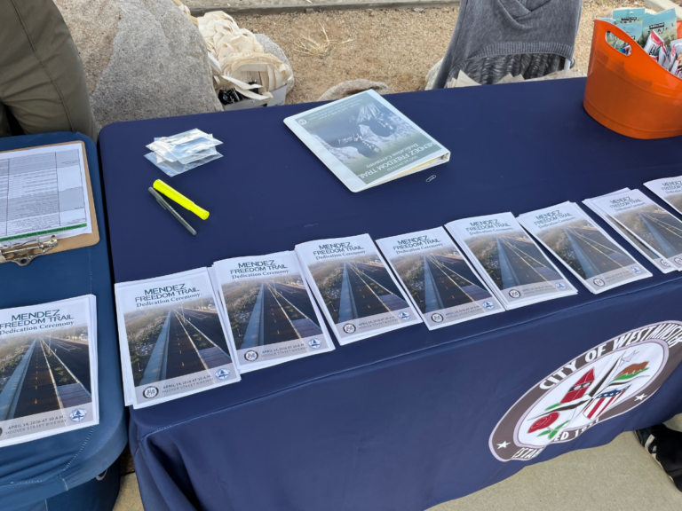 Stacks of Mendez Freedom Trail dedication ceremony programs laid out on a table with City of Westminster branding visible in the background.